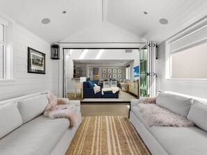 A modern living room with a sofa, a rug, and a view into the kitchen.