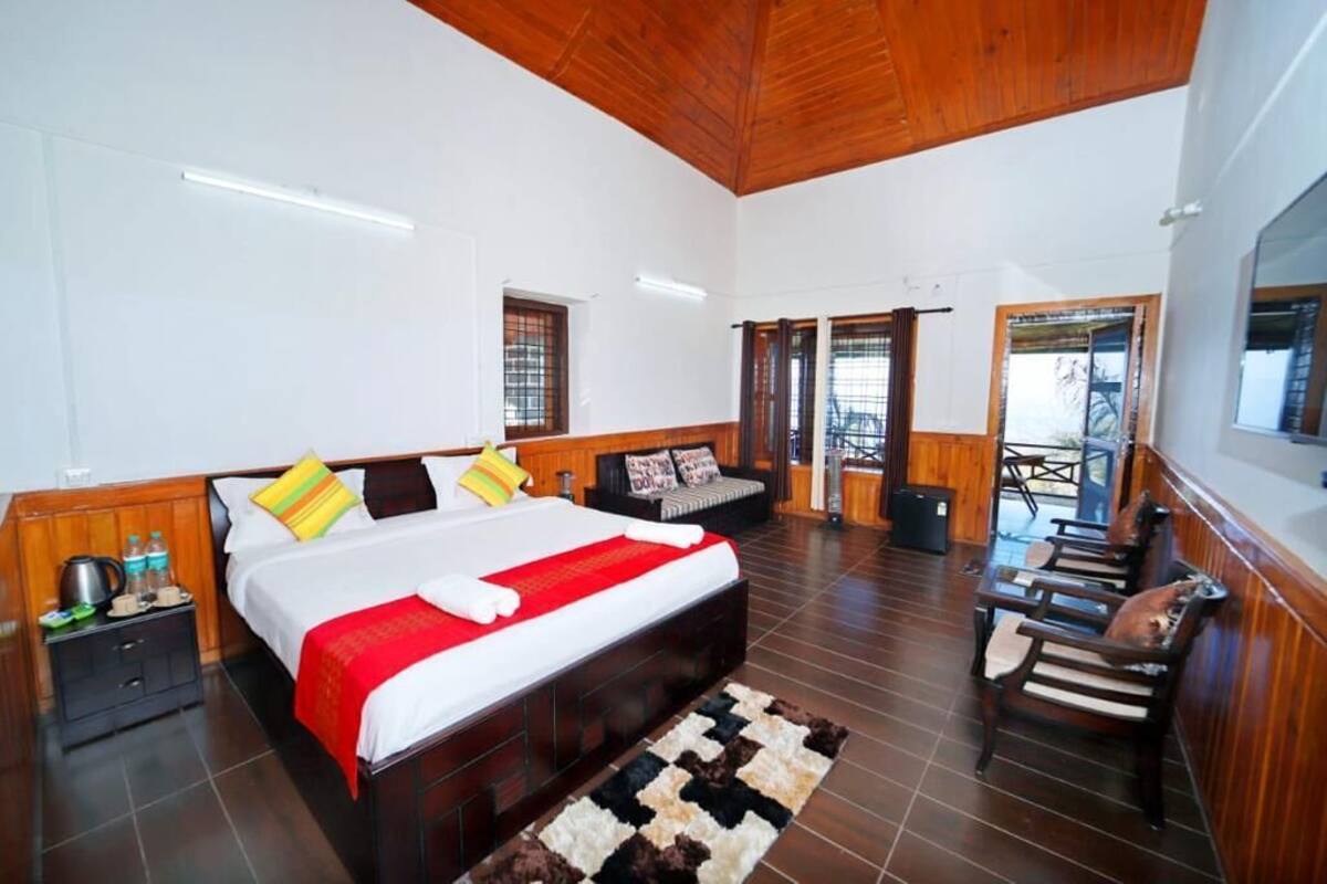 Ein geräumiges Schlafzimmer mit einem großen Bett, Holzboden und einem Balkon mit Sitzgelegenheit.