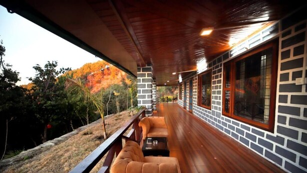 A covered outdoor seating area with wooden benches and a view of a natural landscape.