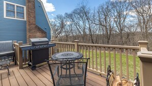 A wooden deck with a barbecue grill, a table, and chairs. - Not-So-Tiny Tiny House with High-Speed Internet, 60-inch TV, Deck, and More! (Galena)