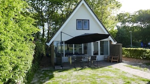 A house with a covered patio, a dining table, and chairs. - Modern, Cosy Family Bungalow Near Beach (Sint Maartensbrug)