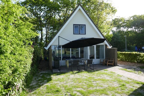Une maison avec un patio couvert, une table à manger et des chaises.