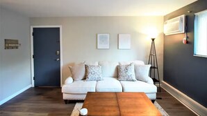 A living room with a white sofa, two side tables, and a floor lamp. - Oak Overflight Oasis Condo-Minutes to WPAFB & WSU with AC, fast WiFi (Fairborn)