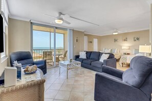 A spacious living area with a balcony, a sofa set, a coffee table, and a TV.