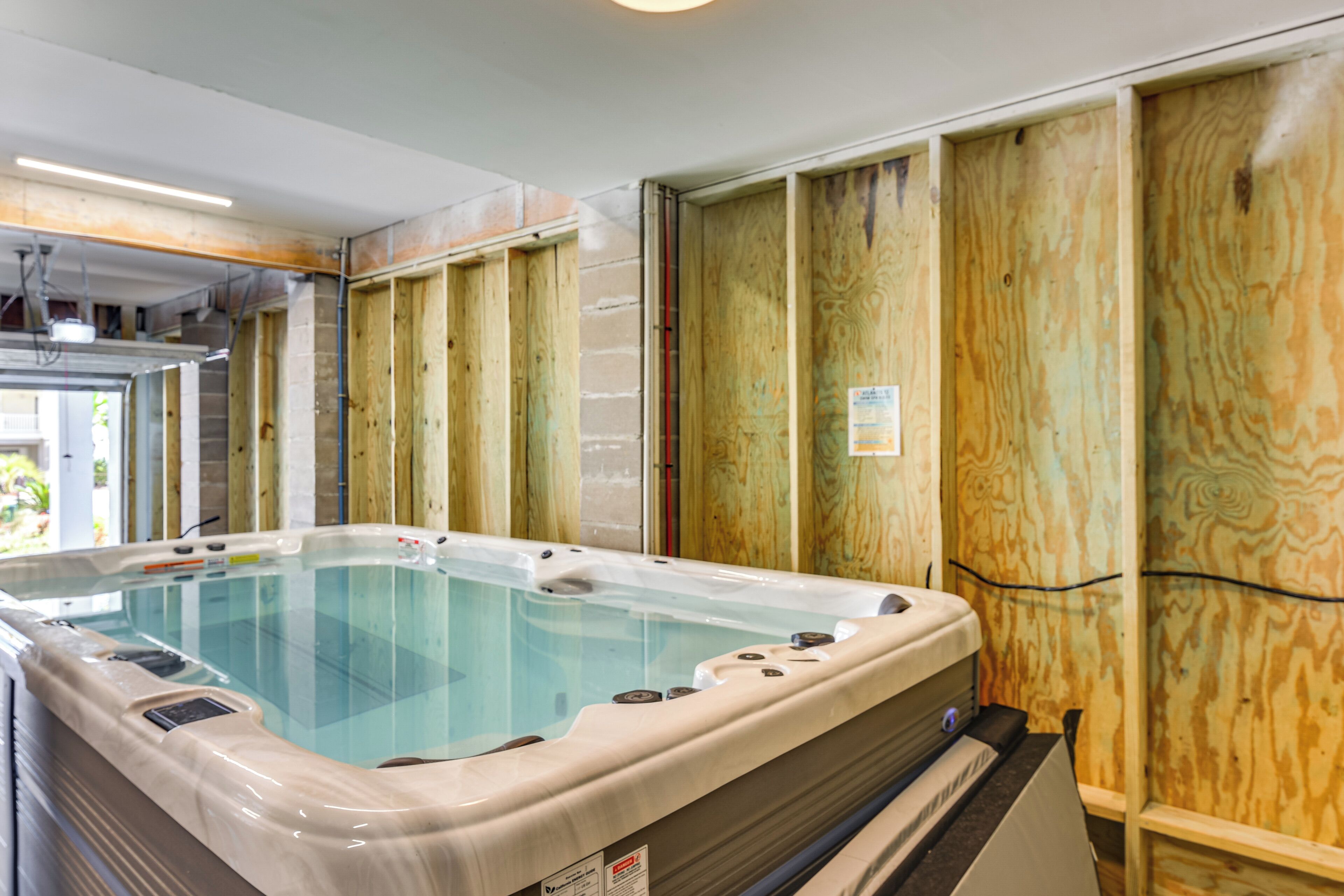 A hot tub in a room with wooden paneling and a visible electrical outlet.