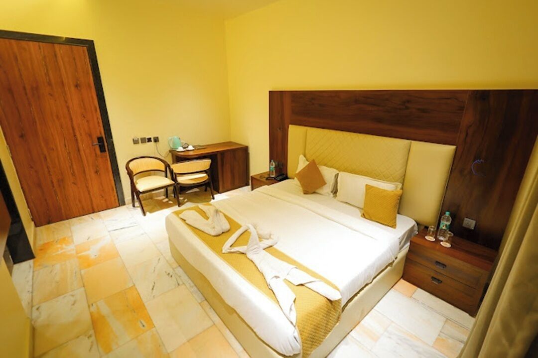 Una habitación de hotel con una cama grande, cabecera de madera, un escritorio con una silla y un armario.