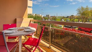 Ein Balkon mit Esstisch, mit Blick auf einen Parkplatz und Gebäude.