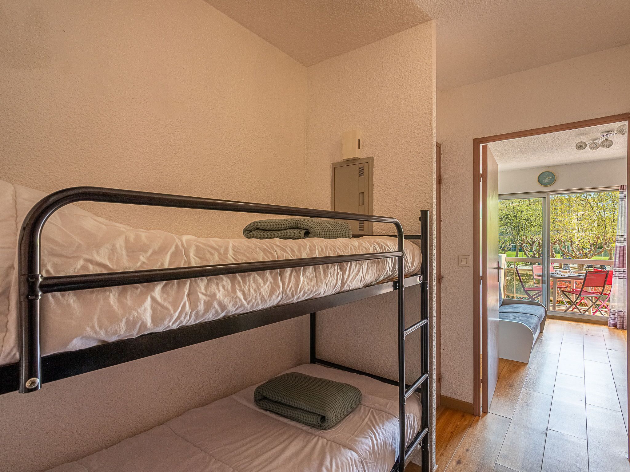 A dormitory room with bunk beds, a small table, and a chair.