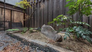 A Zen garden with a rock, gravel, and a wooden fence.