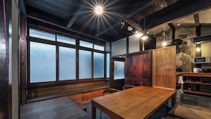 A traditional Japanese-style room with tatami flooring, a wooden dining table, and a sliding door.