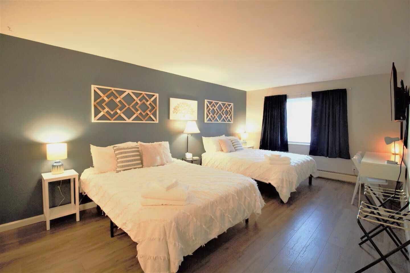 Habitación de hotel con dos camas, un escritorio, una silla y un televisor.