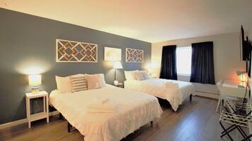 Habitación de hotel con dos camas, un escritorio, una silla y un televisor.
