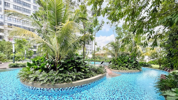 A swimming pool with a mosaic tile design, surrounded by lush greenery and palm trees. - Gaia Residences by Sleepy Bear (Rawang)
