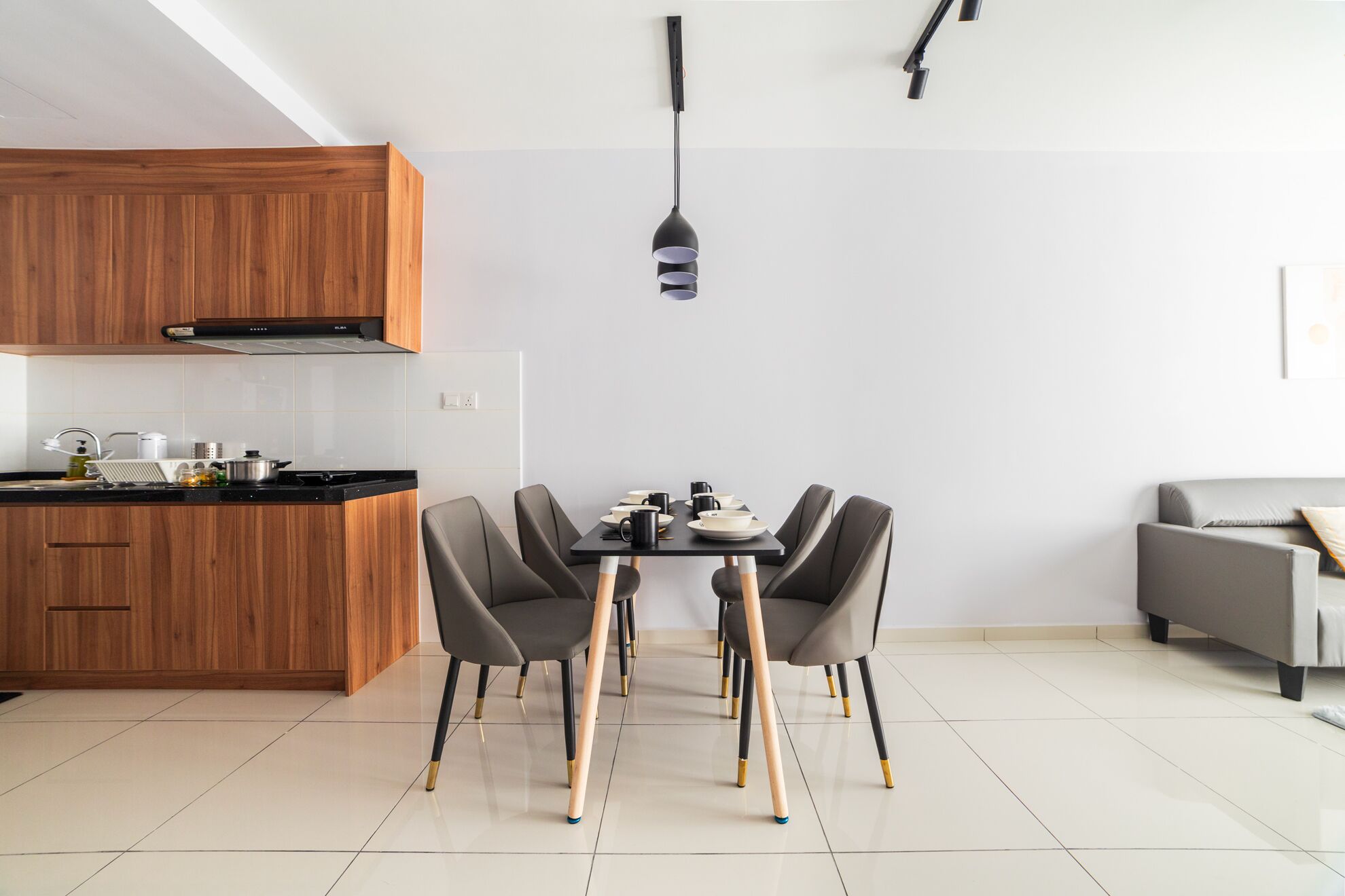 A modern kitchen with wooden cabinets, a dining table with chairs, and a pendant light.