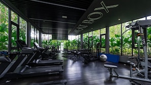 A gym with treadmills, weight machines, and exercise balls, with large windows and a dark wooden floor. - Gaia Residences by Sleepy Bear (Rawang)