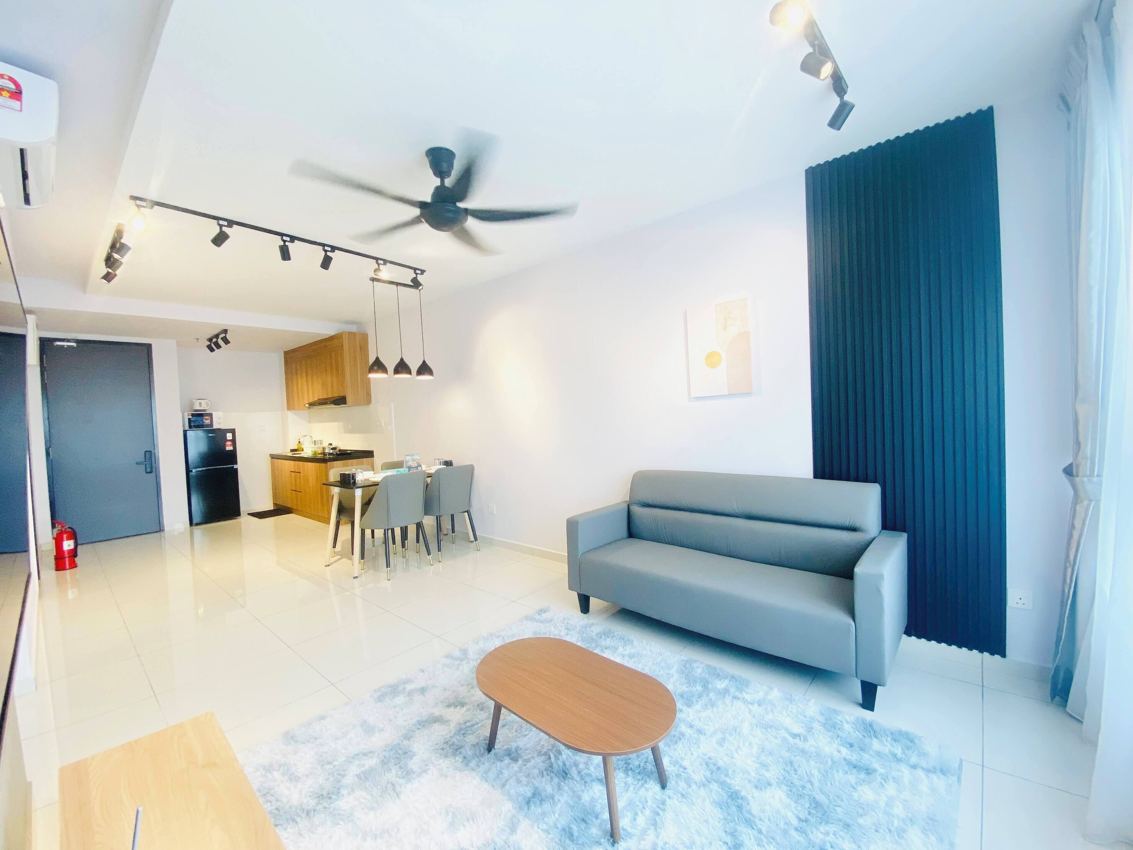 Una sala de estar moderna con un sofá gris, una mesa de centro de madera y un ventilador de techo.