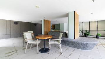 A modern indoor space with a round table and chairs, a grey bench, and potted plants.