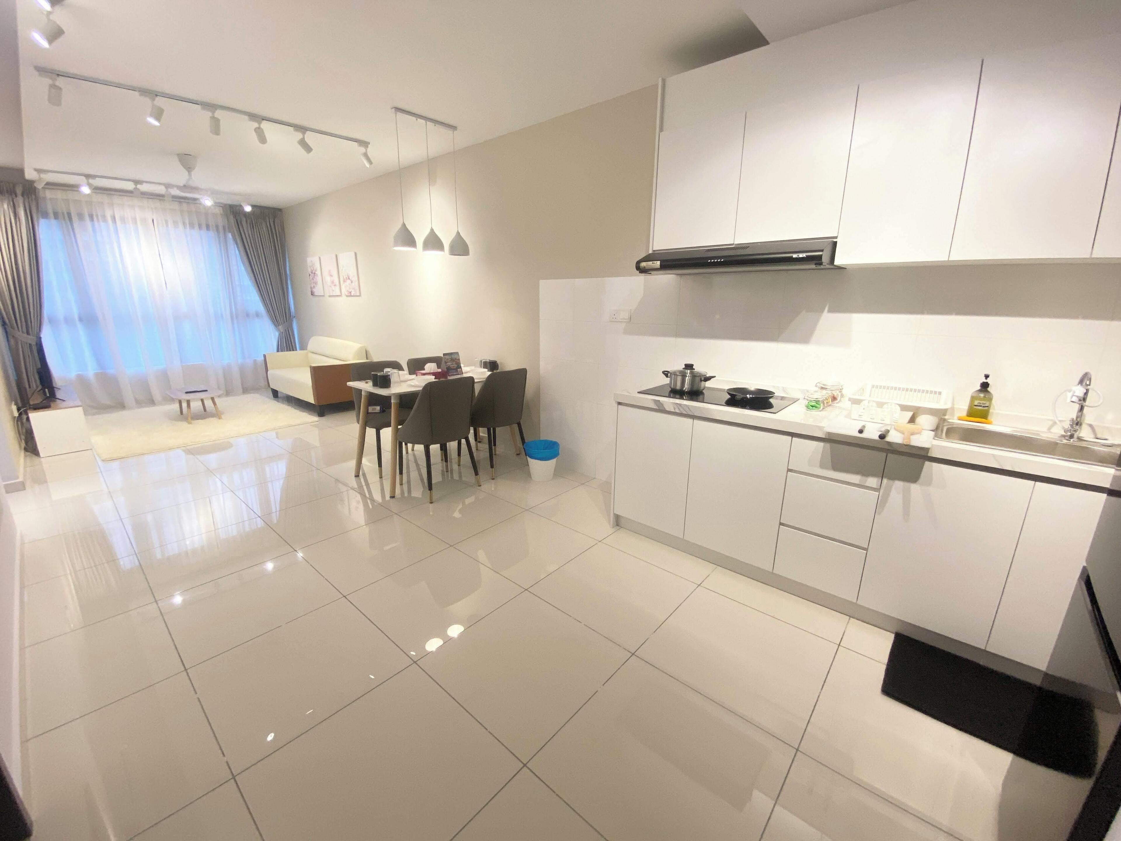 A modern kitchen with white cabinets, a black induction cooktop, and a stainless steel sink.