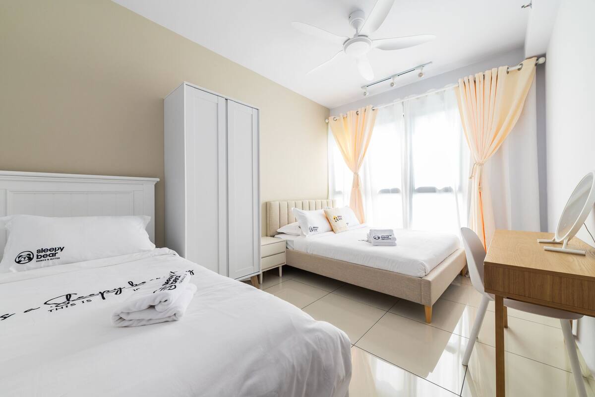 Een hotelkamer met twee bedden, een bureau met spiegel en een kledingkast.
