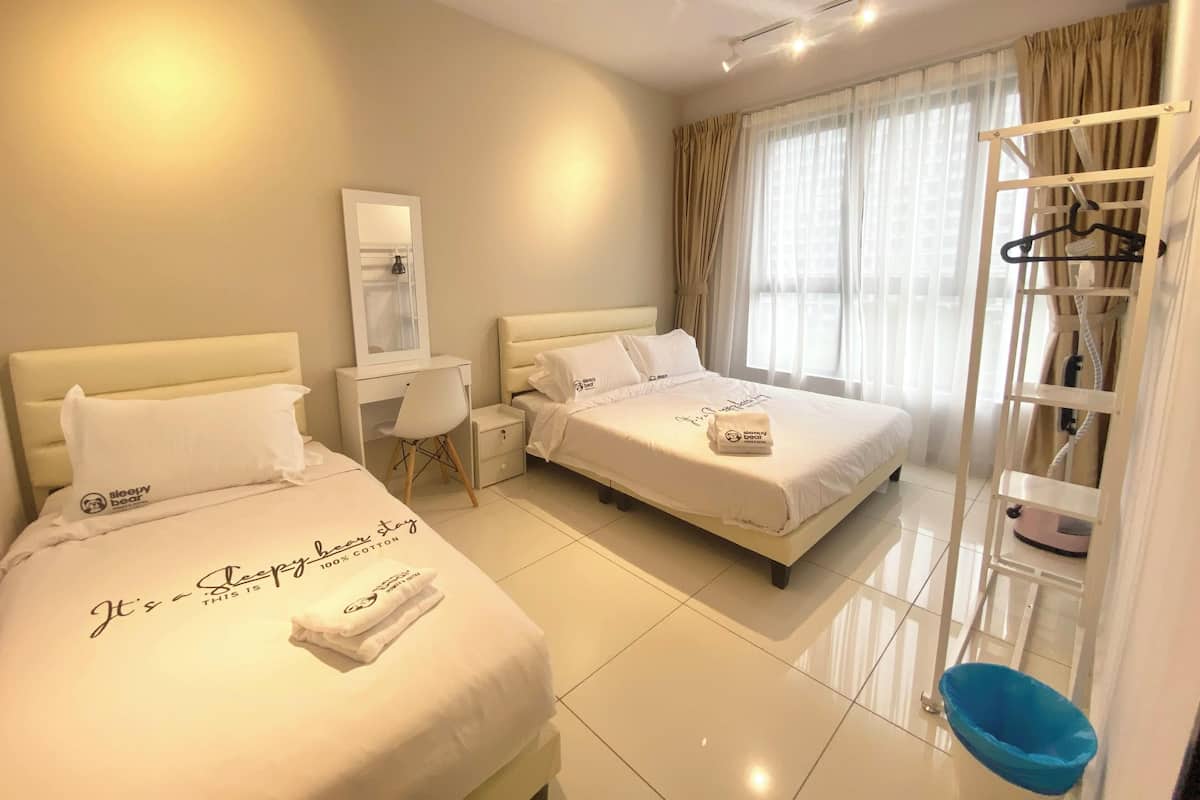 Een hotelkamer met twee bedden, een bureau, een stoel, een kledingkast en een raam met gordijnen.