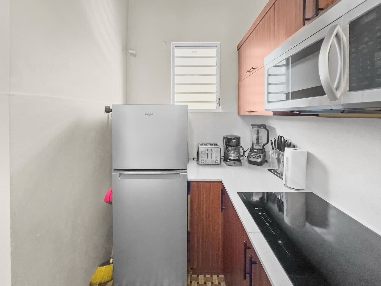 A compact kitchen with a refrigerator, microwave, toaster, coffee maker, and a dishwasher.