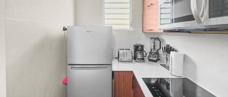 A compact kitchen with a refrigerator, microwave, toaster, coffee maker, and a dishwasher.