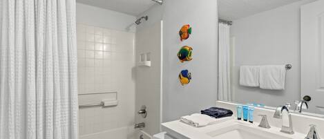 A bathroom with a bathtub, toilet, sink, and a shower curtain.
