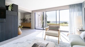 A modern living room with a large sliding glass door leading to a balcony with a view of the sea.