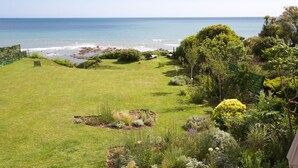 A well-maintained lawn with a view of the ocean, surrounded by various shrubs and trees.