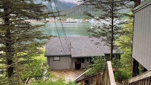 Ein Blick auf eine Hütte mit einer Veranda, die auf einen See mit Blick auf einen dichten Wald blickt.