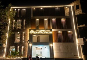 Un hôtel appelé «Hotel Devi Paradise», doté d’une façade moderne, de nombreuses fenêtres et d’une entrée bien éclairée.