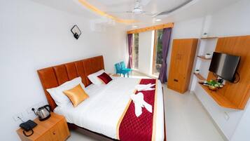 A modern hotel room with a large bed, a wooden nightstand, a TV mounted on the wall, and a window with curtains.