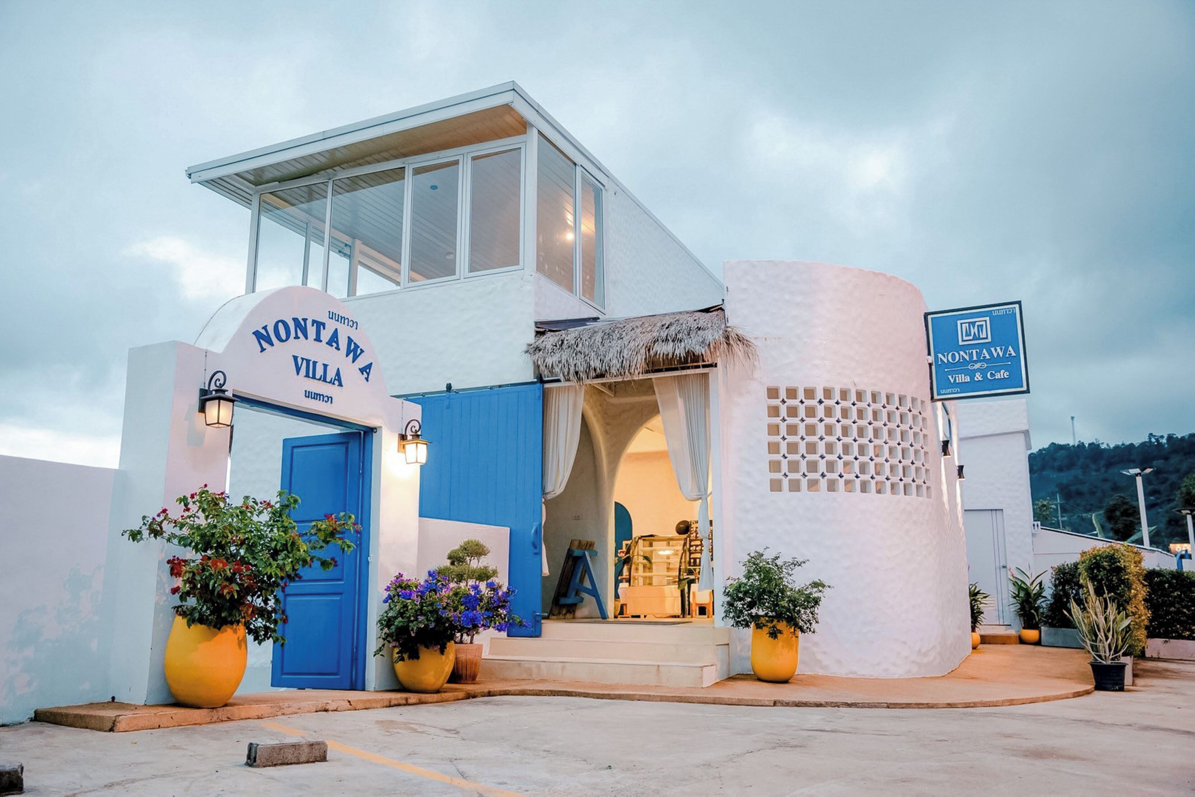 A modern building with a blue door and a sign reading "Nontawa Villa & Cafe."