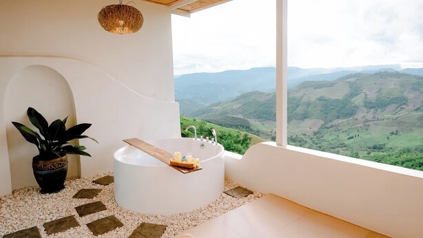 A bathroom with a bathtub, a plant, and a view of a mountainous landscape. - Nontawa Villa Doichang (Mae Suai)