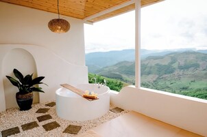Une salle de bain avec une baignoire, une plante et une vue sur un paysage montagneux.