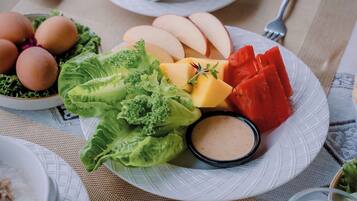 A plate with eggs, lettuce, apples, watermelon, and a dipping sauce.