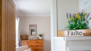 A bedroom with a wooden dresser, a mirror, a bed with pillows, and a sign above the bed that reads "Fâilte". - Taigh Mhurdaidh by Interhome (North Skye)