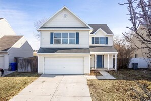 A two-story house with a garage, a covered porch, and a fenced yard.