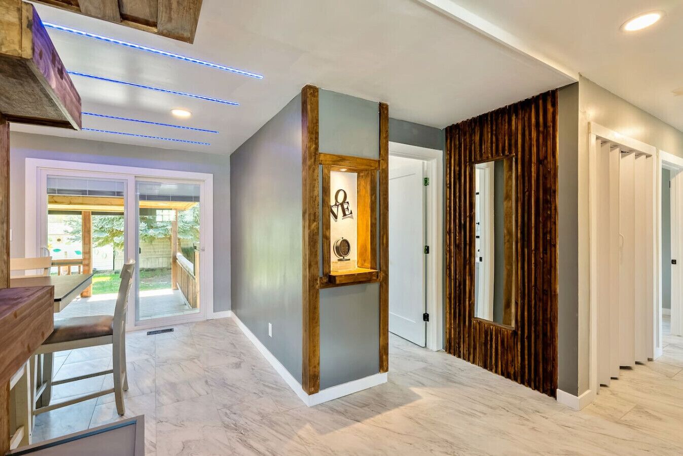 Un interno moderno con una parete decorata in legno, un quadro incorniciato e una scala che conduce a un altro livello.