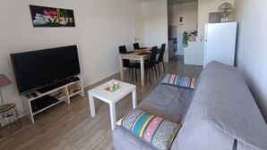 A living room with a TV, sofa, coffee table, and dining area.