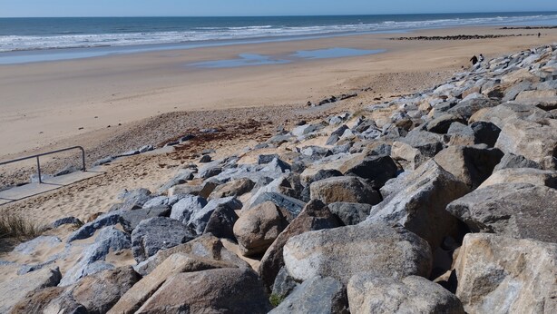 A rocky beach with a sandy area and a view of the ocean.