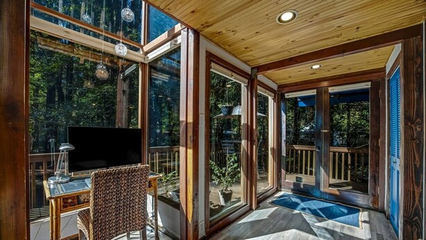 A spacious room with large windows, a television, a desk, and a chair. - Cabana Del Rio, by Vinifera Homes (Guerneville)