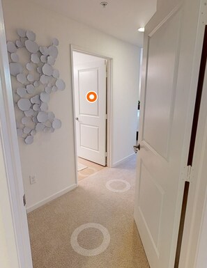 Stylish hallway with a circular accent door and wall art, leading to a clean and simple interior.
