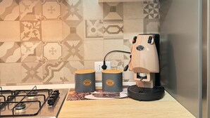 Une cuisine équipée d’une cuisinière à gaz, d’une machine à café et de deux récipients à café.