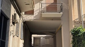 Une ruelle étroite en milieu urbain, bordée d’un immeuble doté de nombreux balcons et d’un garage.