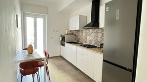 Une cuisine moderne avec des armoires blanches, un réfrigérateur en acier inoxydable et un pare-feu en carreaux.