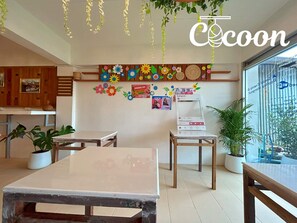A cozy cafe interior with wooden tables, hanging plants, and colorful wall decorations. - Cocoon Chiang Rai City (Chiang Rai)