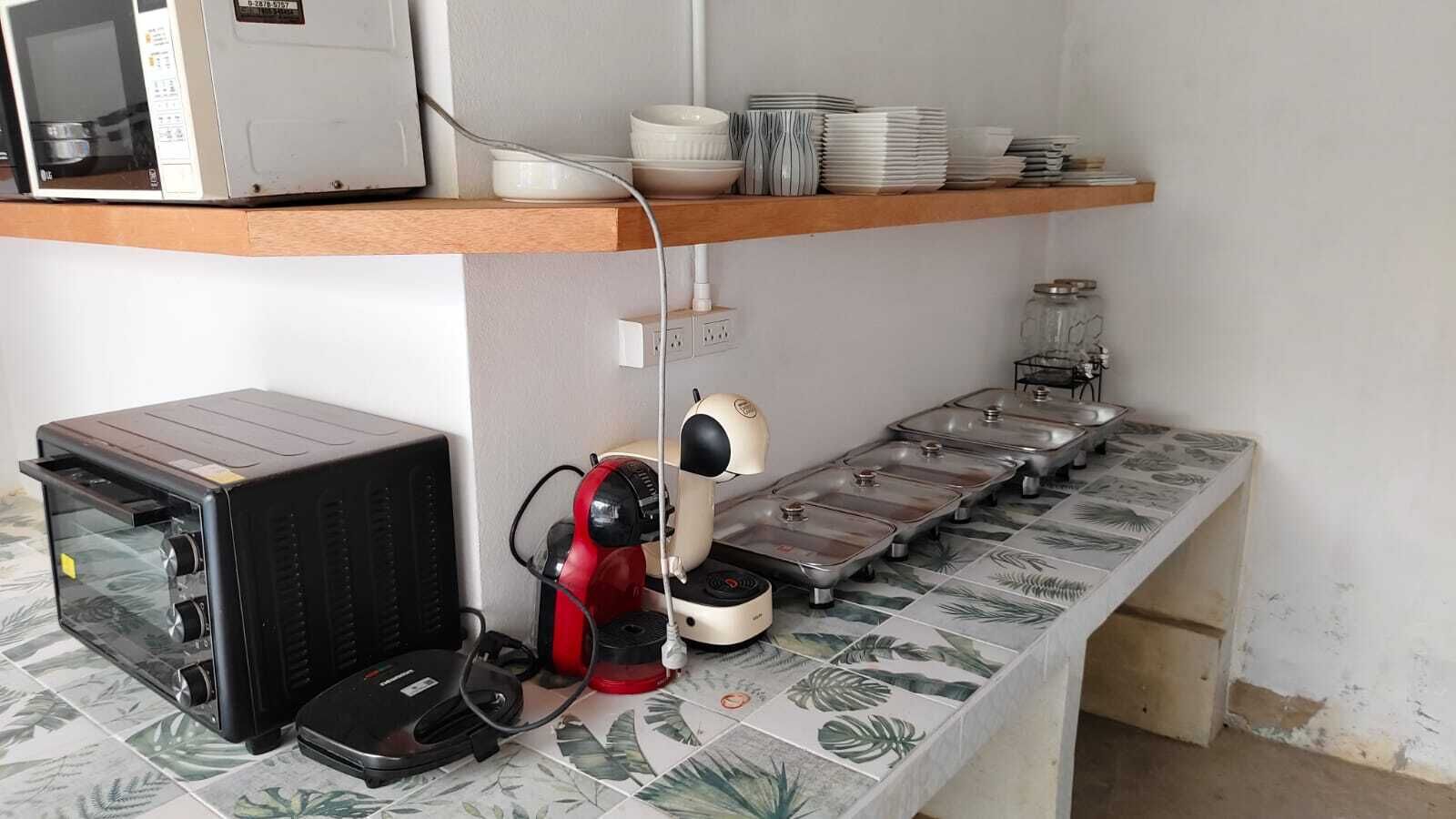 Una cocina con microondas, cafetera y una disposición tipo bufé con varios bandejas de servicio.