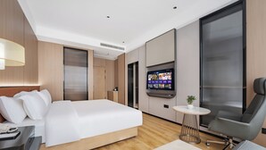 A modern hotel room with a large bed, a desk with a lamp, a TV, and a chair. - Wanzai Yijia La Maison Hotel (Yichun)