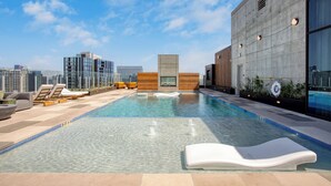 Una piscina en la azotea con agua cristalina, sillas de descanso y vistas a la ciudad.